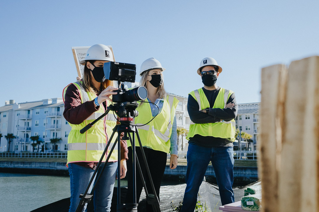 Photoshoot crew members wear hard hats at a construction site