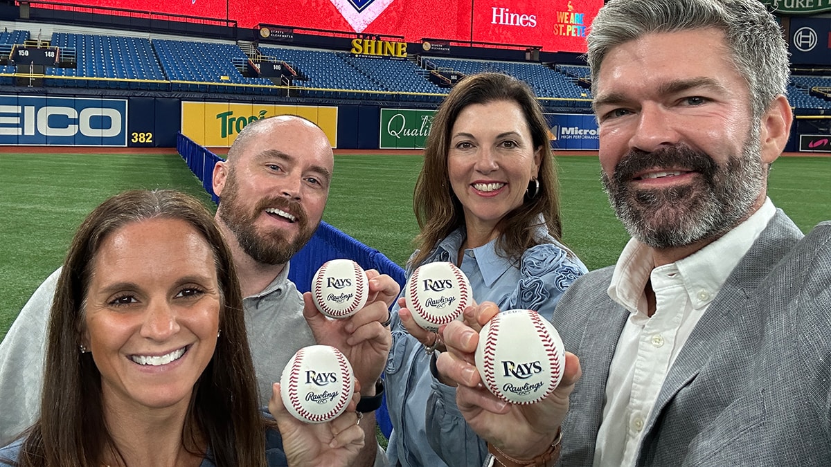 A photo of the CR partner team holding up Rays-branded baseballs at a Tampa Bay Rays stadium event